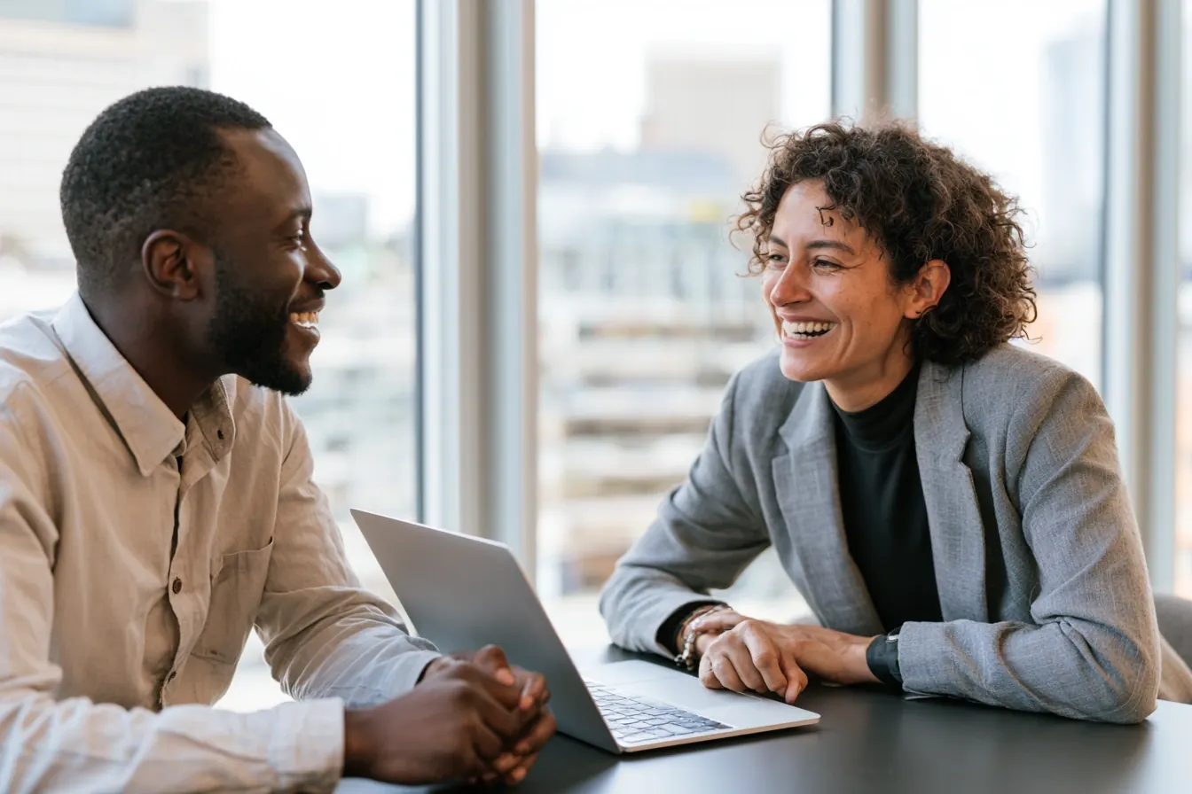 Two financial professionals reviewing loan matching platform on a laptop in a modern office